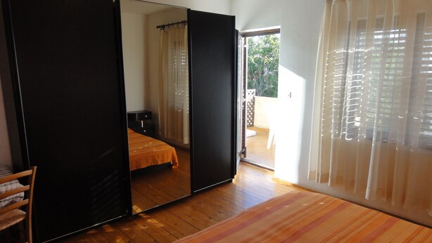 Un dormitorio con cama, armario y puerta corredera que da a un espacio exterior.