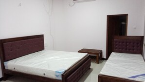 Una habitación con dos camas, una mesita y un aire acondicionado.