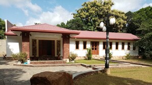 Un edificio con techo rojo, columnas de ladrillo y entrada de piedra.