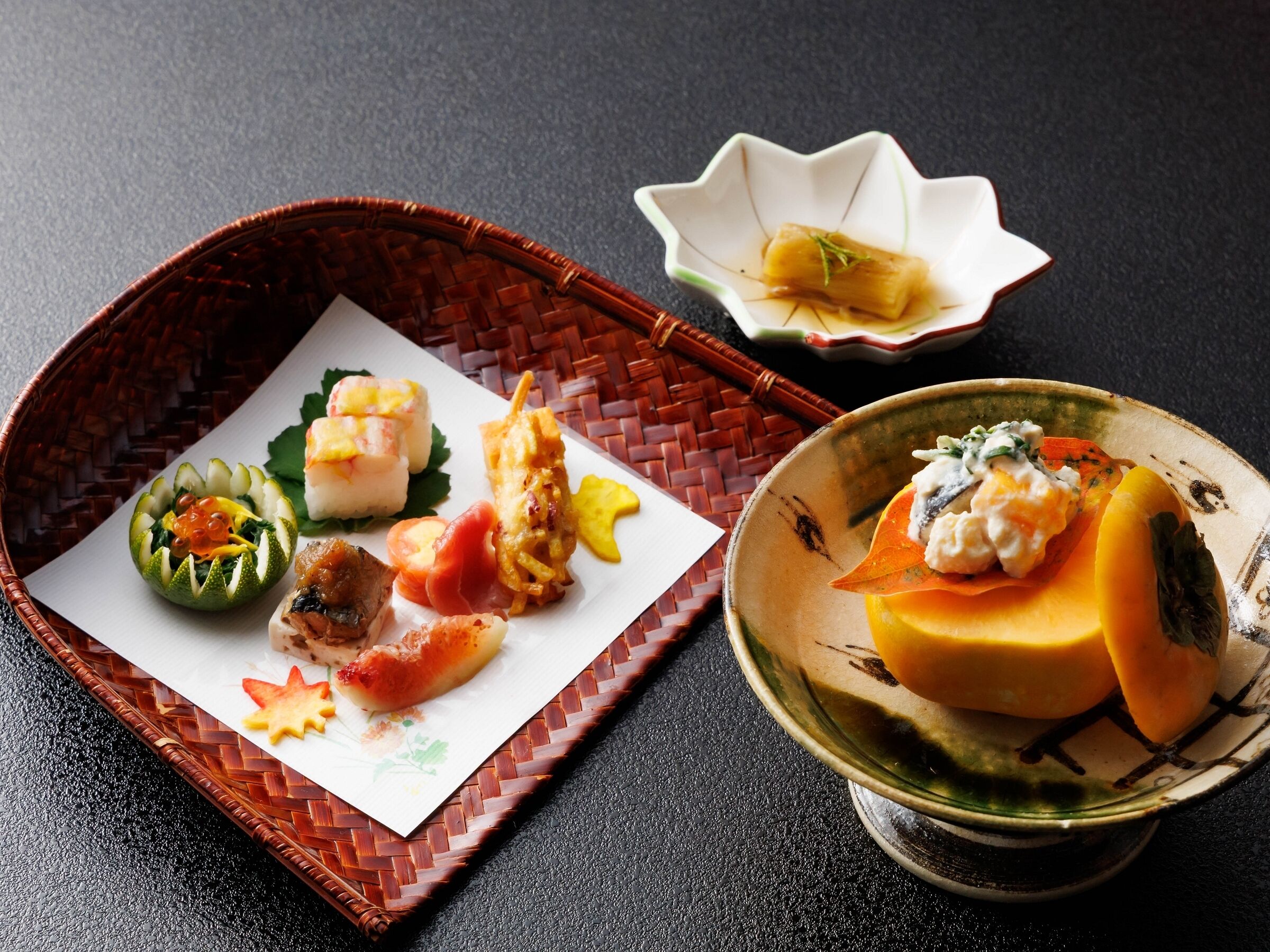 A traditional Japanese meal with various dishes on a woven tray and a ceramic bowl.