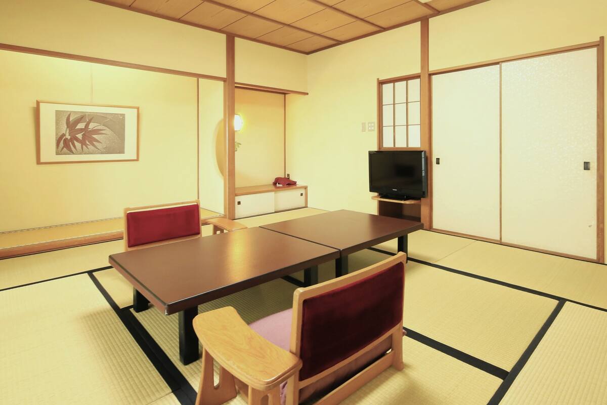 A traditional Japanese room with tatami flooring, a low table, and a television.
