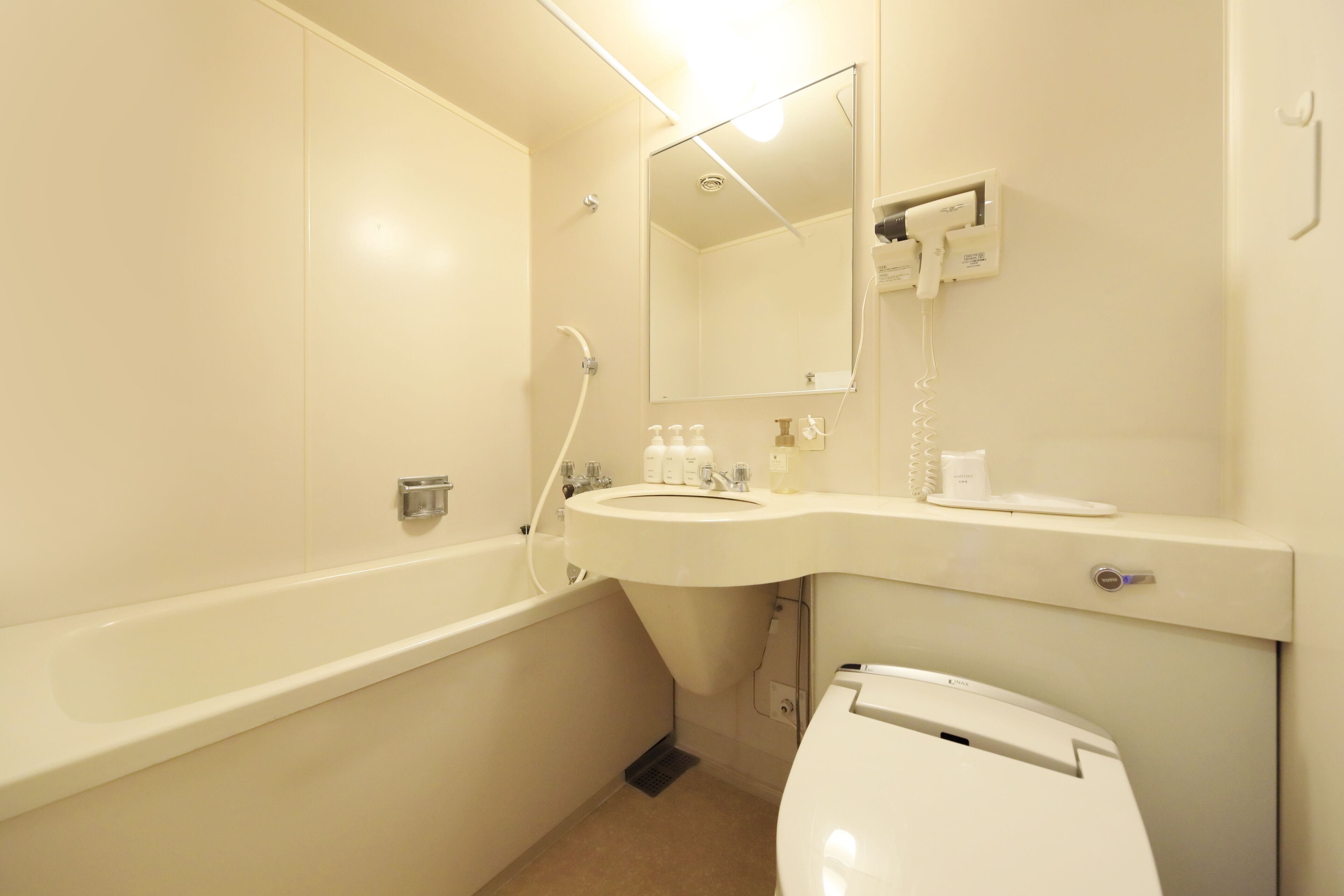 A bathroom with a bathtub, sink, mirror, and toilet.