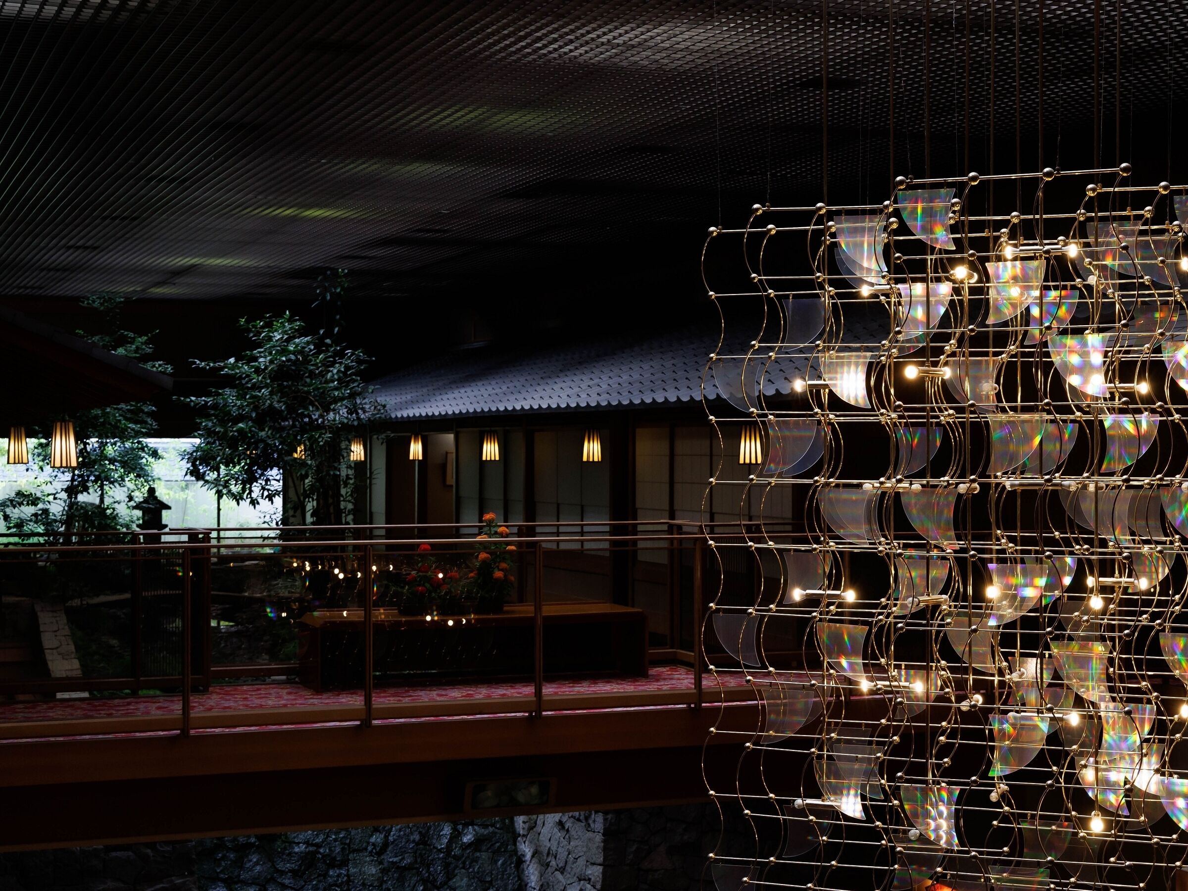 Ein modernes Interieur mit einem einzigartigen Decken­design, ein traditionelles Gebäude im Hintergrund und eine dekorative Lichtinstallation.
