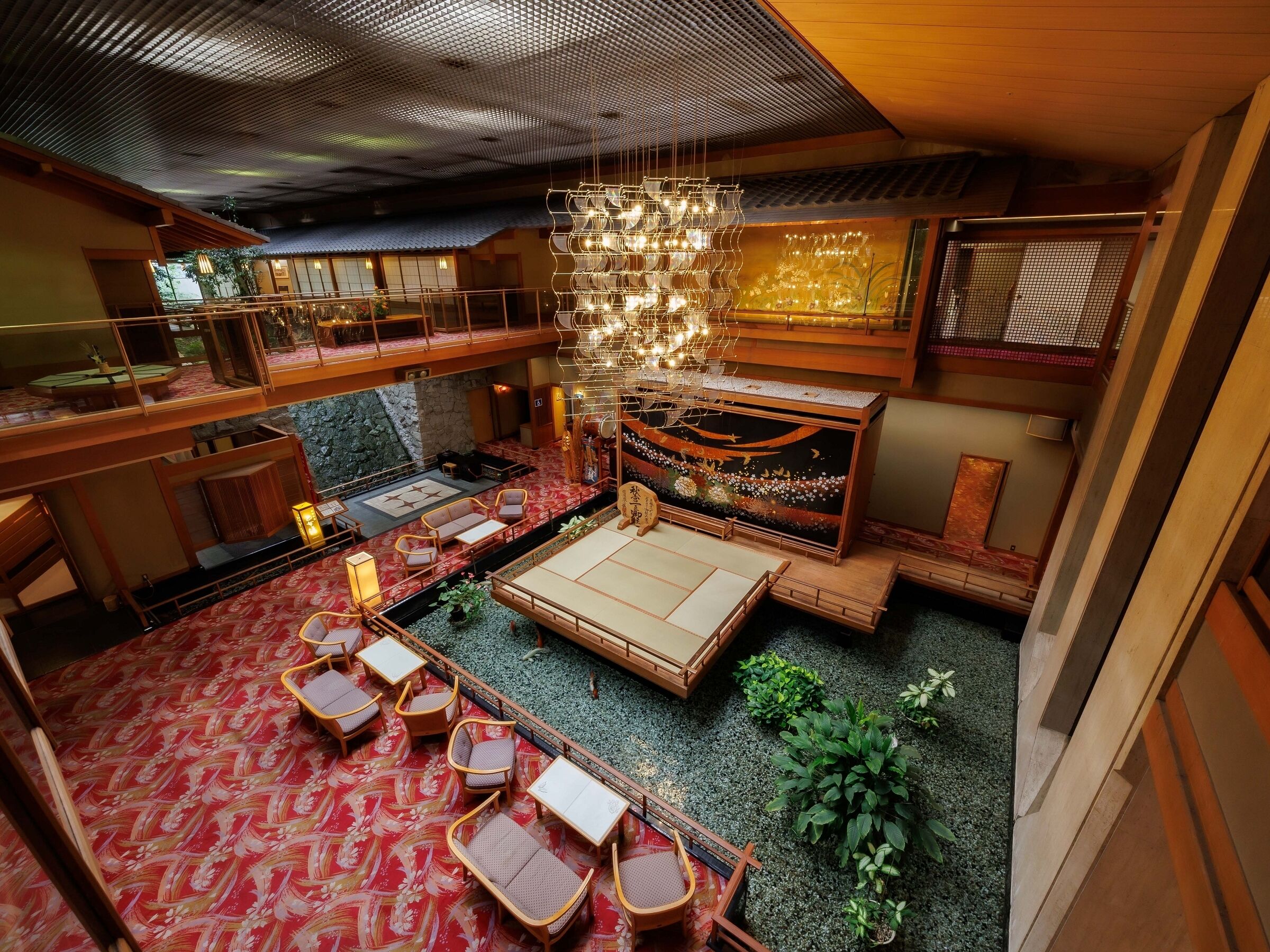 A traditional Japanese-style interior with tatami flooring, low wooden furniture, and a hanging light fixture.