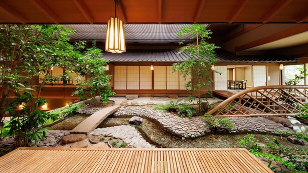 Un intérieur de style japonais traditionnel, avec un sol recouvert de tatamis, un bassin à carpes koï et un pont en bois.