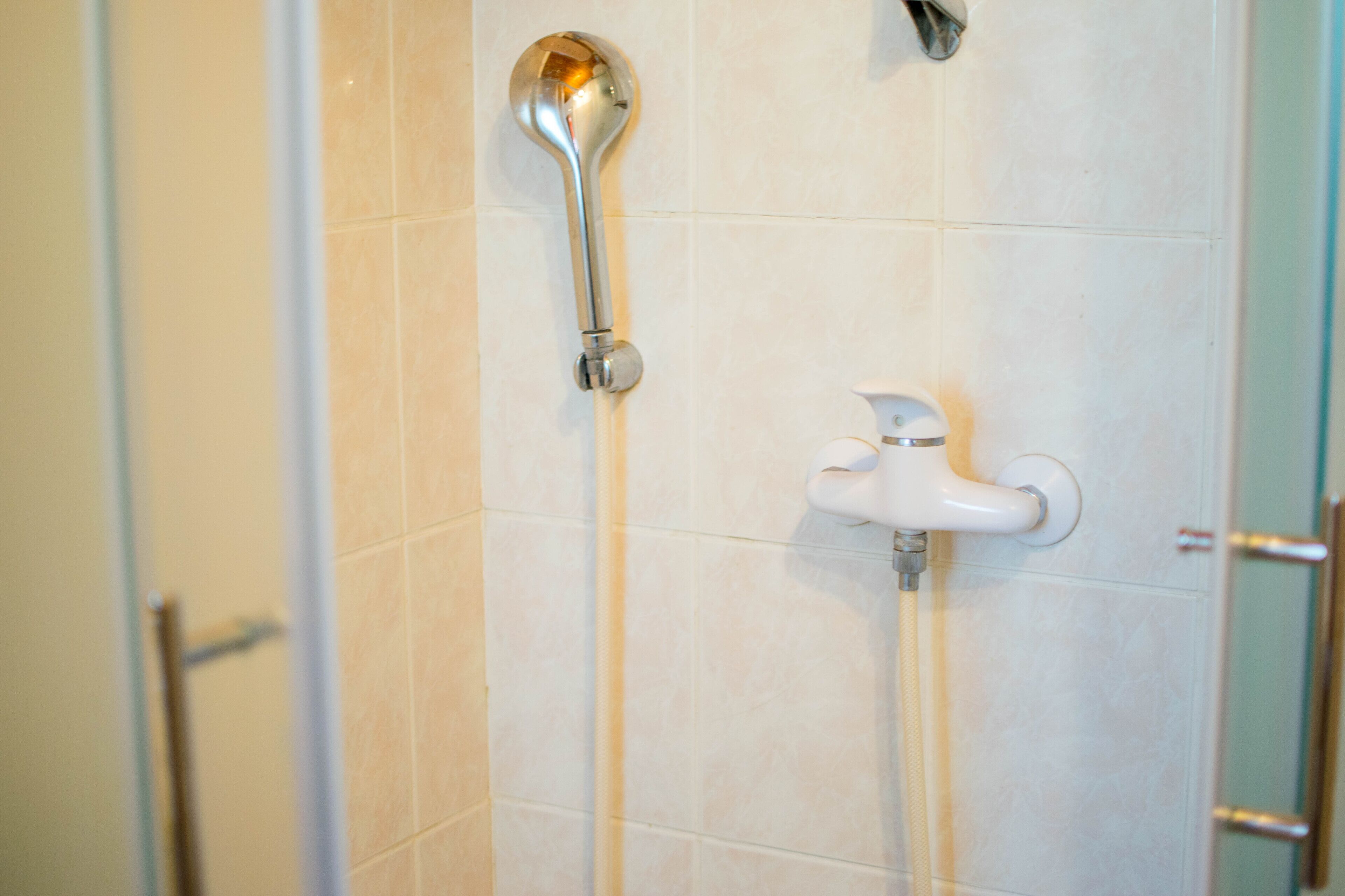 A shower with a handheld showerhead and a wall-mounted faucet.