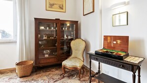 Una habitación con un armario de madera, una silla, una mesa con un juego de mesa y una ventana con cortinas.