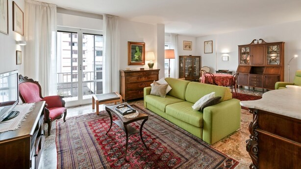 Una sala de estar con un sofá verde, un aparador de madera y un sillón rojo.