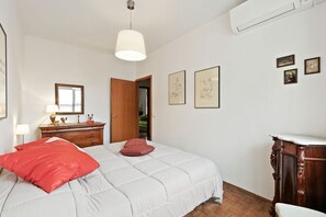 A bedroom with a bed, a dresser, a mirror, and framed artwork on the wall.