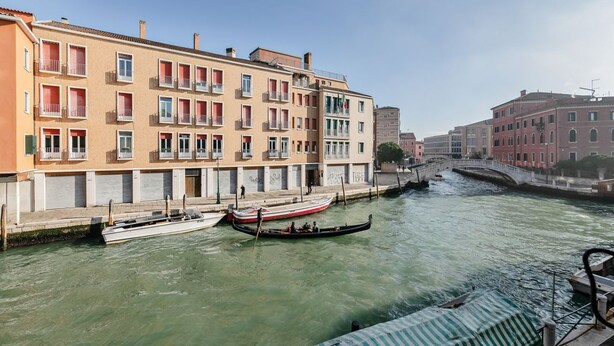 Un canal amb gondoles, un pont i edificis amb balcons.