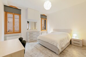 Een slaapkamer met een bed, nachtkastje, kaptafel en een raam.