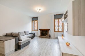 Een moderne woonkamer met een bank, open haard en een lange tafel met decoratieve objecten.