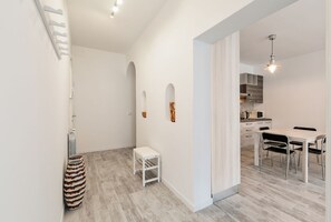 Una cocina moderna con armarios blancos, una mesa de comedor con sillas y una lámpara colgante.