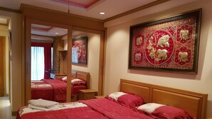 Ein Hotelzimmer mit einem großen Bett, einem Holz-Kopfteil, einem Spiegel und einem Wandbild mit Elefanten.