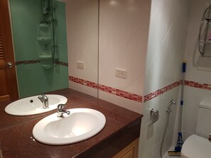 A bathroom with two sinks, a shower, and a toilet.