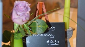 Um buquê de rosas roxas com uma placa preta indicando uma garrafa de Chardonnay de 25L por €4,90.