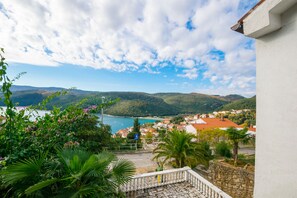 A coastal town with a view of the sea, hills, and a white building with a balcony. - Apartment Misura - Peaceful Location (Labin)