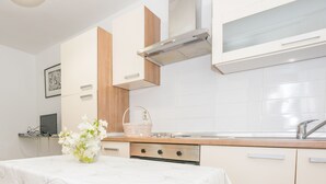 Une cuisine moderne avec des armoires blanches, une hotte de cuisinière en acier inoxydable et un plan de travail en bois.