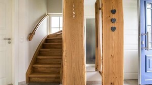 Un escalier en bois avec une rampe, une porte bleue et un mur décoré de motifs en forme de cœur.