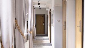 A corridor with wooden doors, some with numbers, and a rope tied to the curtains. - SeaSide Sopot (Sopot)