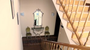 A staircase with wooden balusters and a carpeted floor leading to a landing with two chairs and a table. - B&B Elio's Place (Seveso)