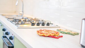 Una cocina con encimera blanca, estufa a gas y dos individuales tejidos.