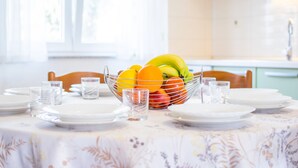 Una mesa de comedor dispuesta con platos, vasos y un frutero.
