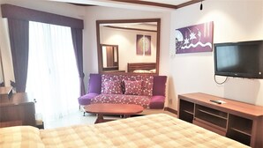 A hotel room with a large bed, a sofa, a TV, and a small table. - Seaview Floor 11 Jomtien Beach (Pattaya)