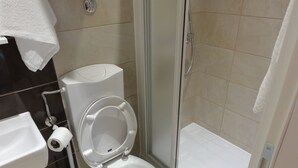 Une salle de bain avec des toilettes, une douche et un lavabo.
