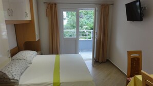 Une chambre avec un lit, une chaise, une télévision et un balcon.