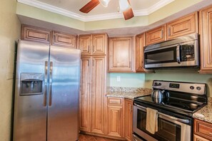 Una cocina con armarios de madera, un refrigerador de acero inoxidable, un microondas y una estufa.