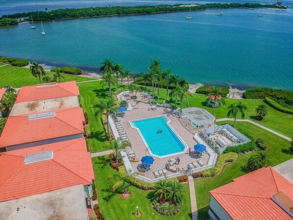 Un resort con piscina, sillas de descanso y vista al océano.