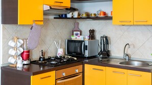 Una cocina con gabinetes amarillos, un microondas, una estufa y varios utensilios de cocina.