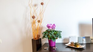 Un escritorio con una planta en maceta, ramas decorativas y una pequeña mesa con un juego de té.