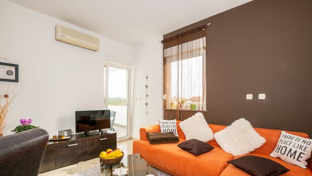 Una sala de estar moderna con un sofá naranja, una mesa de centro de vidrio y un televisor de pantalla plana.