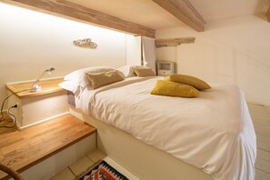 Una camera da letto con un letto, un comodino, una lampada e un piccolo tavolino da notte.