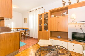 A compact living space with a kitchenette, dining area, and a seating area with a TV. - Apartments Mirjana (Pula)