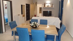 Een moderne eetruimte met een houten tafel, blauwe stoelen en een decoratieve vaas.