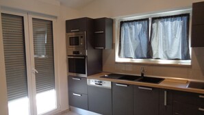 Een moderne keuken met inbouwapparatuur, een raam met gordijnen en een schuifdeur met glas.