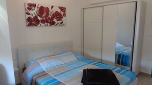 Een slaapkamer met een bed, een kledingkast en een schilderij aan de muur.