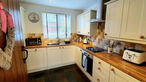 A kitchen with white cabinets, a wooden countertop, a toaster, a sink, and a window with blinds. - Vale View Cottages - The Stables Cottage 5 Star. Near beach & town, Pets welcome (Prestatyn)