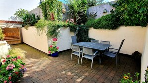 A patio with a table and chairs, surrounded by potted plants and flowers. - Vale View Cottages - The Stables Cottage 5 Star. Near beach & town, Pets welcome (Prestatyn)