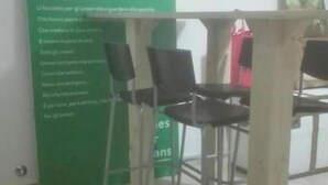 Une pièce avec un mur vert, un tableau blanc sur lequel est écrit du texte et une table entourée de chaises.