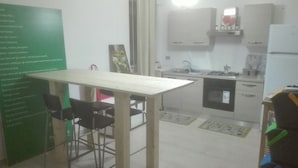 Une petite cuisine équipée d’une table et de chaises, d’un réfrigérateur, de placards et d’un évier.