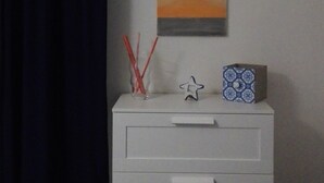 Une pièce avec une commode blanche, un tableau et un climatiseur fixé au mur.