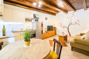 A cozy living room with a wooden dining table, a sofa, and a TV.