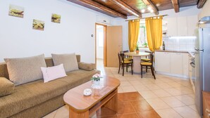 Ein gemütliches Wohnzimmer mit einer Couch, einem Holztisch und einem Essbereich mit Tisch und Stühlen.