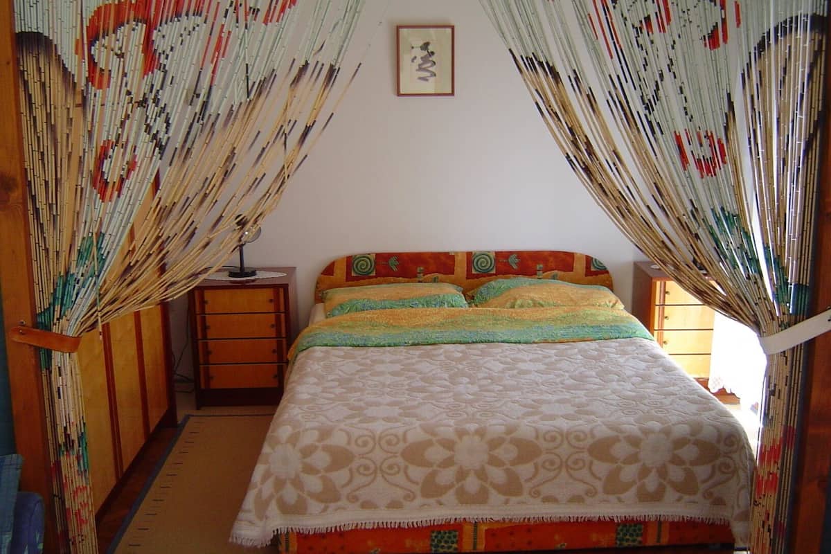 A bedroom with a bed, a nightstand, and a wall-mounted picture.