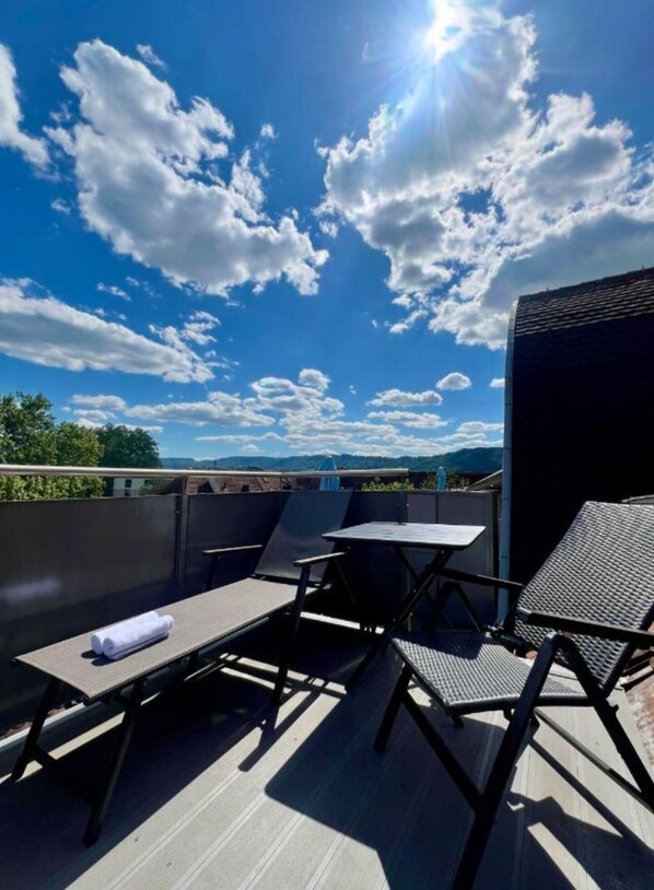 A rooftop terrace with a table and chairs, a view of the sky, and distant mountains. - Seefeld Residenz GmbH (Zürich)