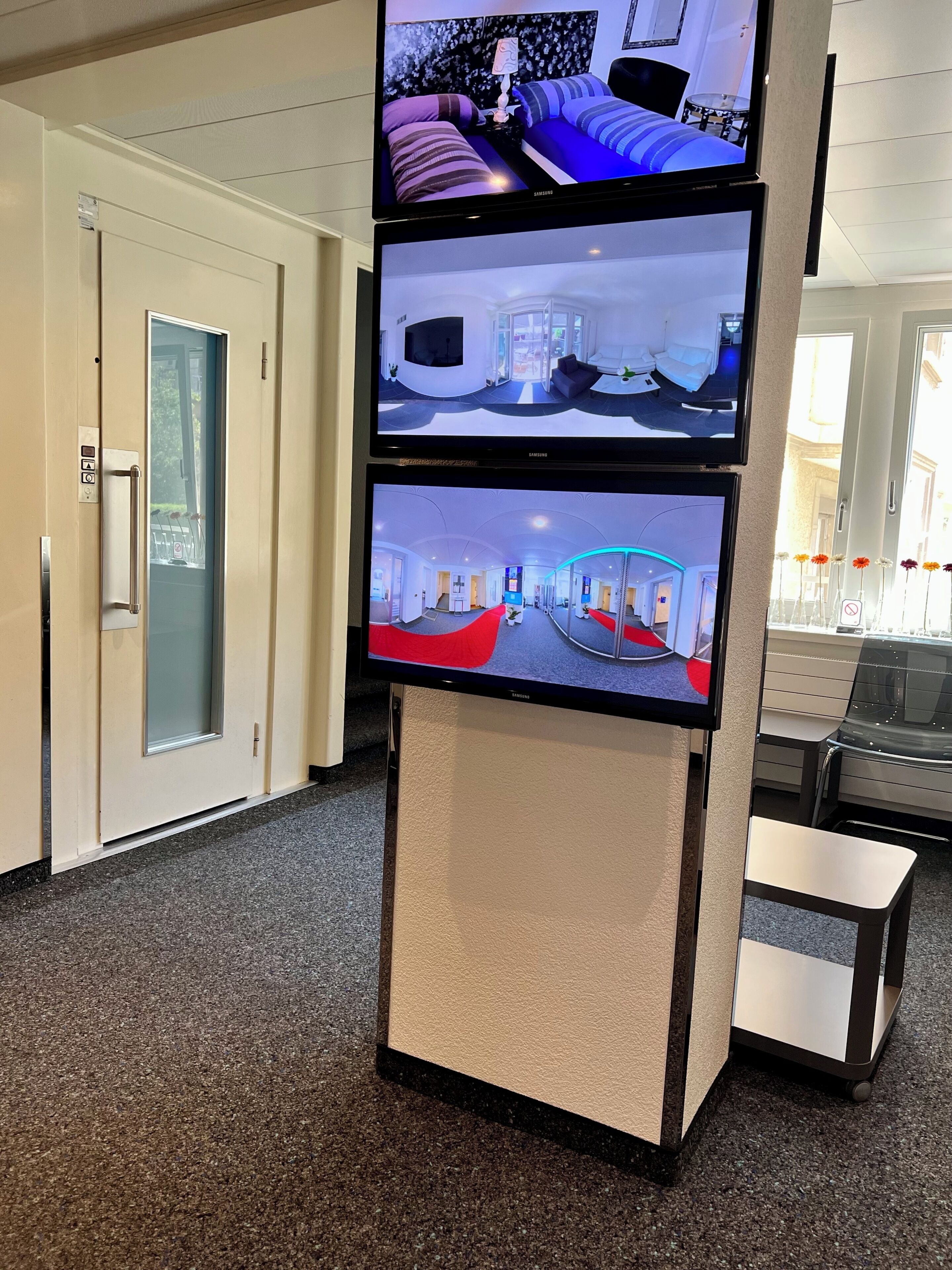 A hotel reception area with a digital display showing different room views.